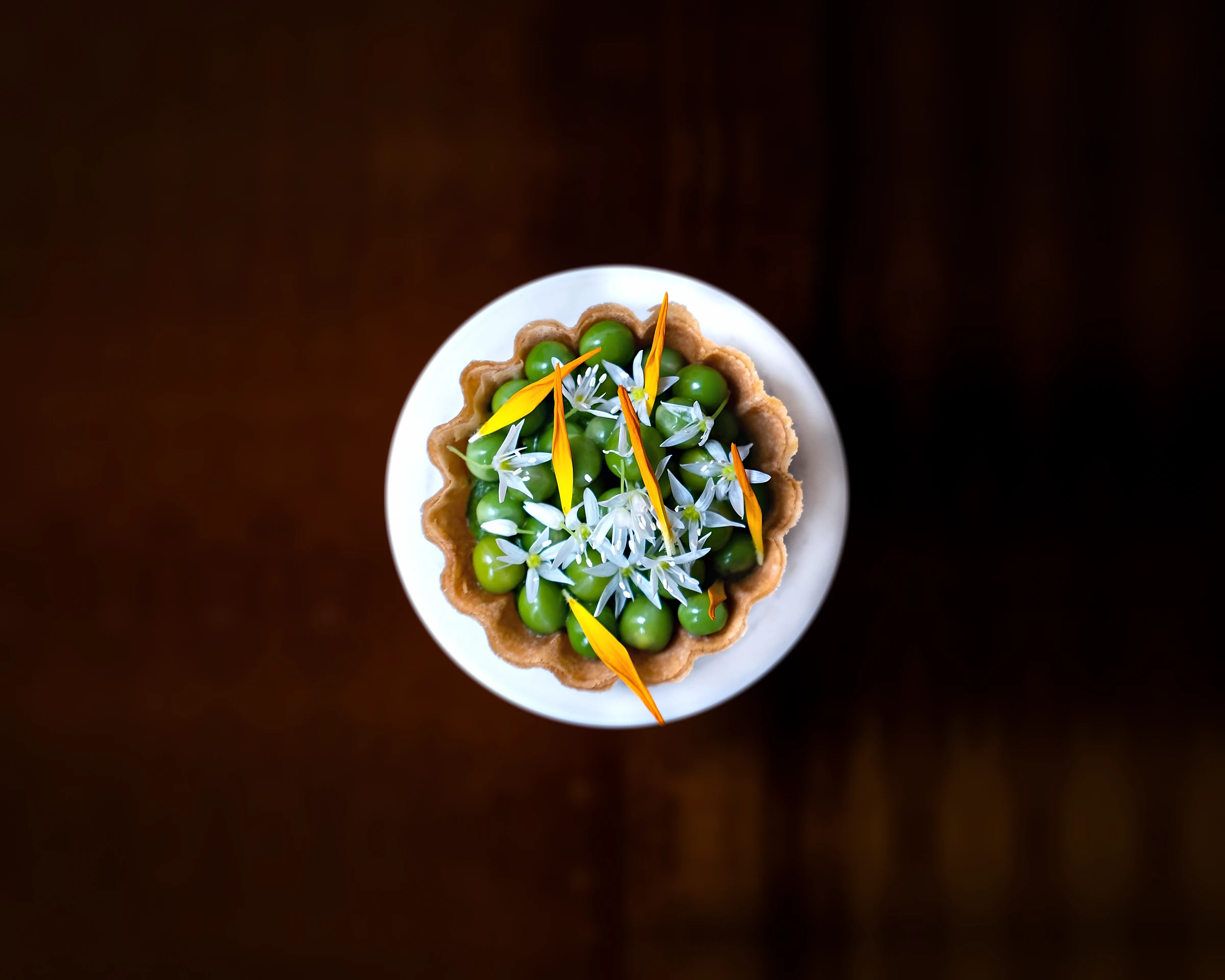 Tartelletta di piselli, fiori di aglio orsino e petali di calendula, vista dall'alto
